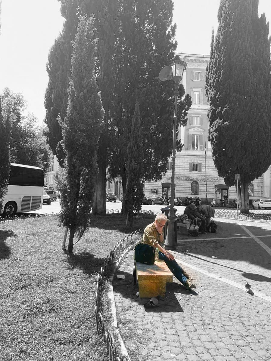 A man sitting alone on a park bench in Piazza dei Quiriti